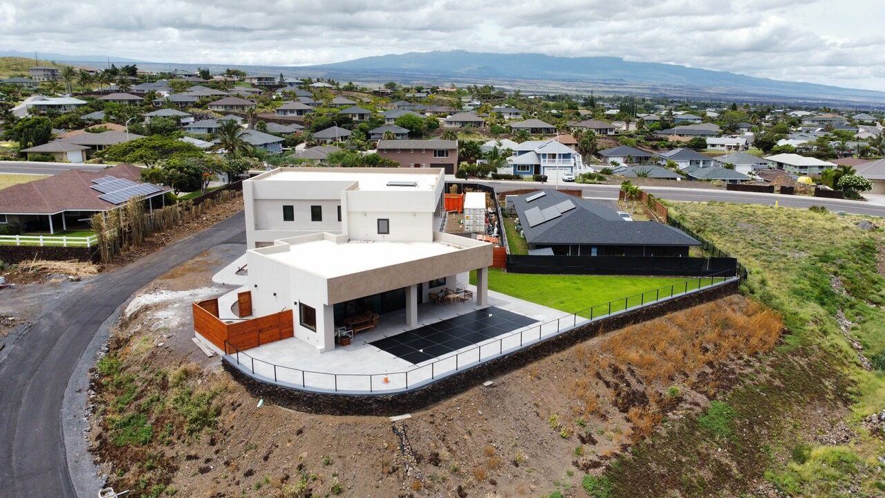 Drone view of a modern two-story estate above the Kona coastline